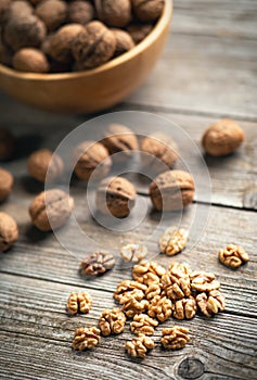 Fresh walnut kernels and whole walnuts in a bowl on rustic old wooden table. photo