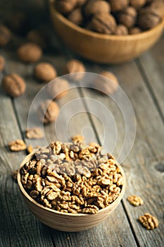 Fresh walnut kernels and whole walnuts in a bowl on rustic old wooden table. Healthy organic food, BIO viands, natural background