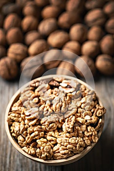 Fresh walnut kernels and whole walnuts in a bowl on rustic old wooden table. Healthy organic food, BIO viands, natural background