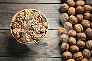 Fresh walnut kernels and whole walnuts in a bowl on rustic old wooden table. photo