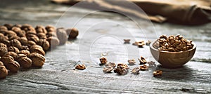 Fresh walnut kernels and whole walnuts in a bowl on rustic old wooden table. photo