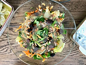 Fresh Walnut Salad with Grated Carrot Slices in Glass Bowl at Dinner Table