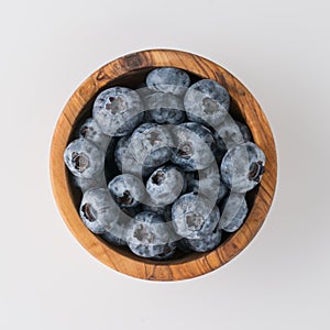 Fresh washed organic blueberries ina olive wood bowl topv view isolated on white