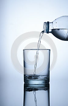 fresh water flowing from plastic bottle into a glass