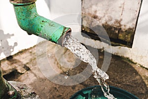 Fresh water gushes out from a deep well manual hand pump into a pail for bathing and other uses