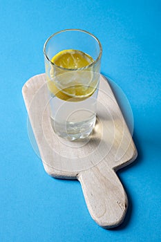 Fresh water with lemon on kitchen board on blue background