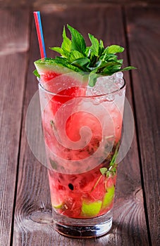 Fresh watermelon drink smoothie with mint, ice and lime in glass on wooden background