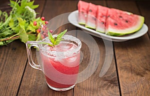 Fresh watermelon juice on a background of slices wooden table. Close-up