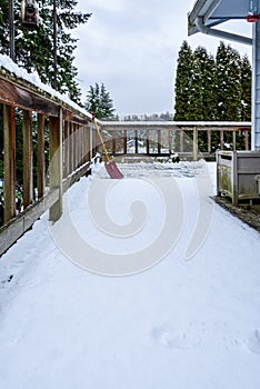 Fresh wet snow on a cedar deck, with snow shovel, view of snow-covered neighborhood