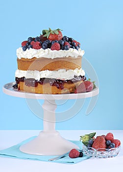 Fresh whipped cream and berries layer sponge cake on pink cake stand