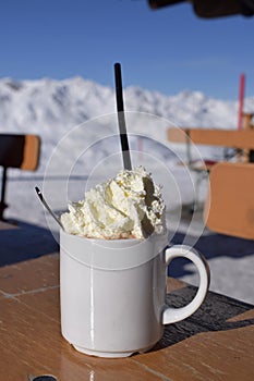 Fresh whipped cream and hot chocolate on snowy mountain photo