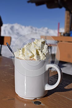 Fresh whipped cream and hot chocolate on snowy mountain photo