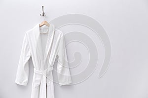 Fresh white bathrobe hanging on wall. Space for text