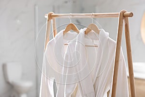 Fresh white bathrobes hanging on rack