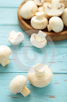 Fresh white champignon mushrooms on blue wooden background. Vertical photo