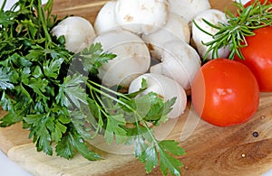 Fresh white champignons mushrooms, tomatoes, parsley and thyme on cutting board. Vegan concept.