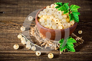 Fresh white currant in ceramic bowl on dark wooden background.