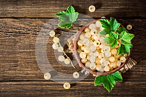 Fresh white currant in ceramic bowl on dark wooden background.