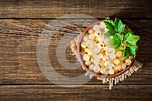 Fresh white currant in ceramic bowl on dark wooden background.