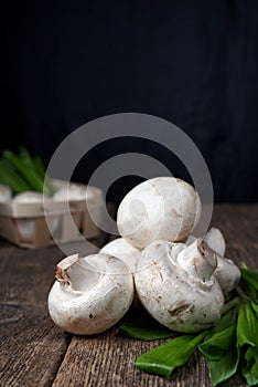 Fresh white mushrooms champignon in brown bowl on wooden background. Top view.
