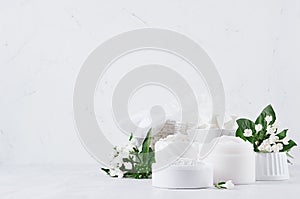 Fresh white natural wedding cosmetics - white cream, salt, clay, towel, bath accessories, flowers on soft light white wood table.