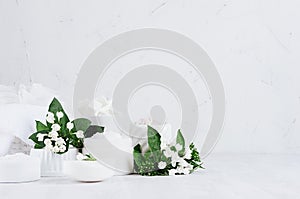 Fresh white natural wedding cosmetics - white cream, salt, clay, towel, bath accessories, flowers on soft light white wood table.