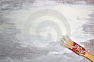 Fresh white paint on wooden background. Old paintbrush with paint and lying on lower corner.