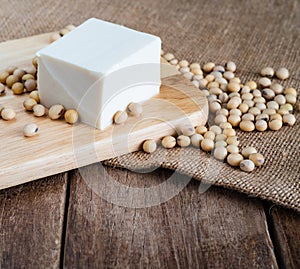 Fresh white soft Japanese tofu on wooden plate with soy bean on gunny sack cloth