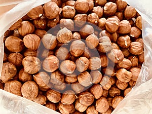 Fresh whole peeled hazelnuts in a open plastic bag in soft focus