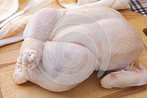 Fresh whole raw chicken on wooden cutting board