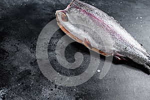 Fresh whole trout fishes. Black background. Top view. Copy space