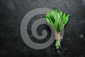 Fresh wild garlic leaves on black background. Wild leek. Top view.