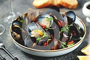 Fresh wild mussels in shells with green onions, garlic, parsley, chili pepper, white wine and olive oil.