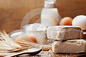 Fresh yeast and ingredients for baking on wooden kitchen table. Product for preparing pizza or bread.