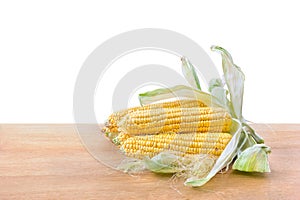 Fresh yellow cobs of maize with kernels ( corn ) on wooden table on white background with space for text