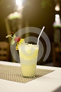 Fresh yellow cocktail with ice and pineapple, lemon slice standing on the table, alcoholic beverages