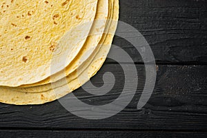 Fresh yellow corn tortillas, on black wooden table background, top view flat lay  with copy space for text