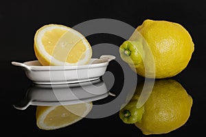 Fresh yellow lemon isolated on black glass