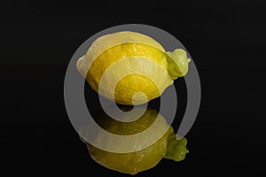 Fresh yellow lemon isolated on black glass