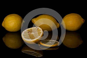 Fresh yellow lemon isolated on black glass