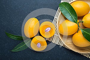 Fresh yellow marian plum fruit (Mayongchid) in Thai name) on black stone. Top view