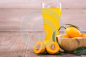 Fresh yellow marian plum fruit (Mayongchid in Thai name) and juice in glass on wooden table