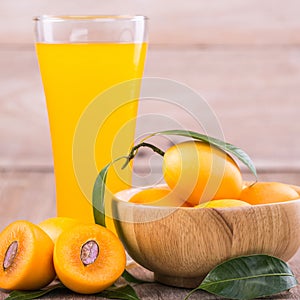 Fresh yellow marian plum fruit (Mayongchid in Thai name) and juice in glass on wooden table