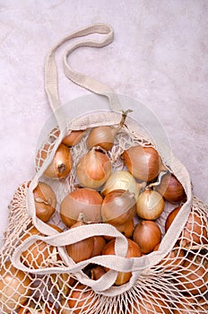 Fresh yellow onions in a knitted bag