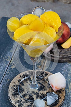 Fresh yellow peach ice-cream scoops in glass cone on the beach,