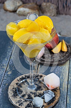 Fresh yellow peach ice-cream scoops in glass cone on the beach,