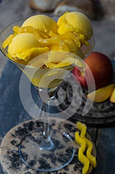 Fresh yellow peach ice-cream scoops in glass cone on the beach,