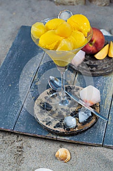 Fresh yellow peach ice-cream scoops in glass cone on the beach,