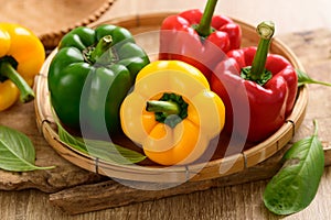 Fresh yellow, red and green bell peppers in a bamboo basket