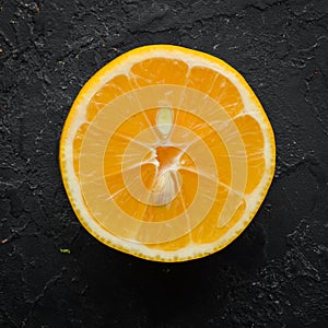 Fresh yellow sliced lemons on black stone background. Citrus fruits. Top view.